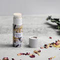 Lip balm with packaging labeled 'Sunset Party' on a light surface with dried flowers.