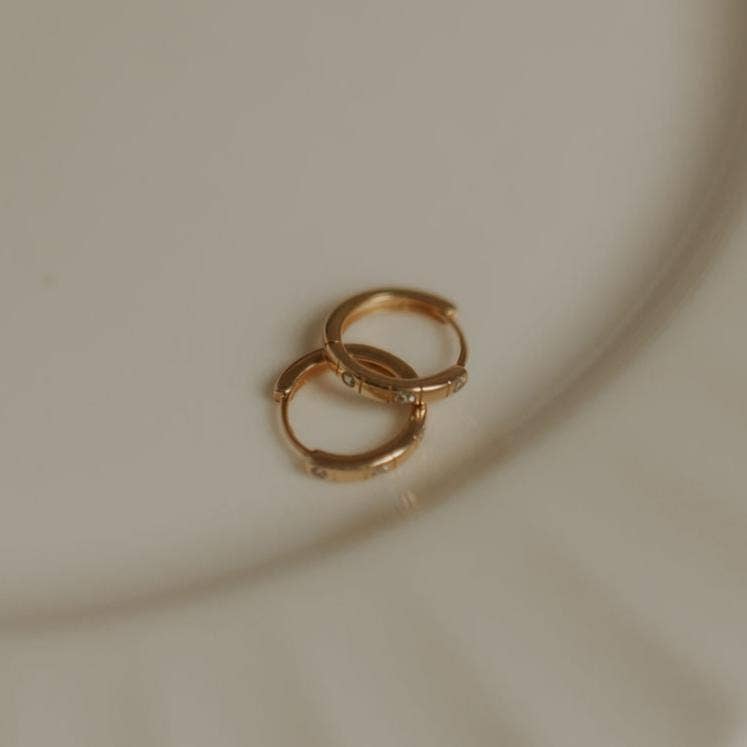 Gold hoop earrings on a beige plate
