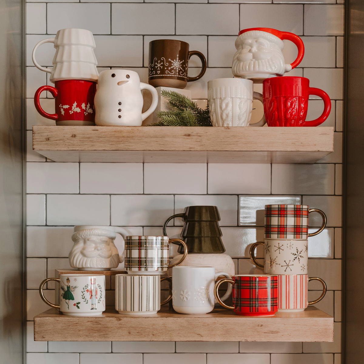 Christmas mugs displayed on wooden shelves, including green striped, plaid, Santa, snowman, and tree designs.

