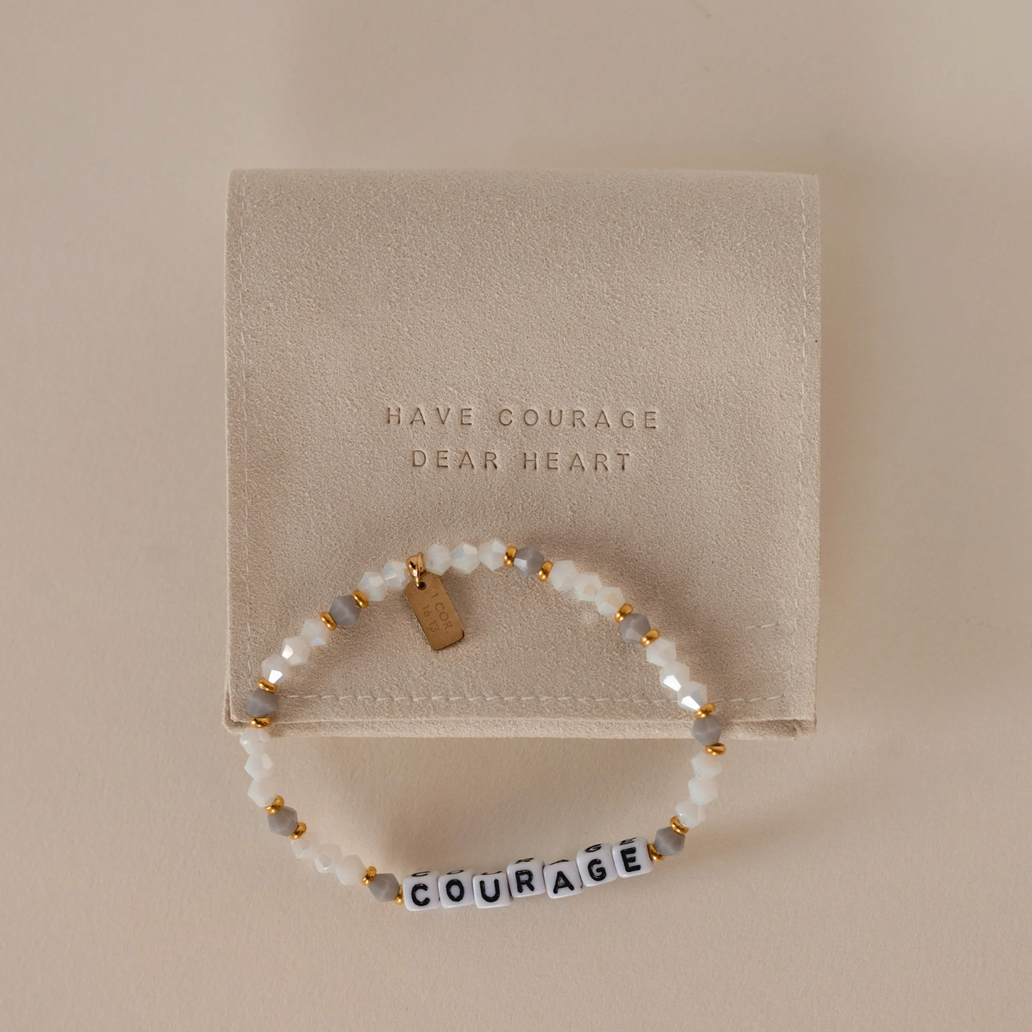 Pearl bracelet with letter beads spelling 'COURAGE' on a beige card with text.