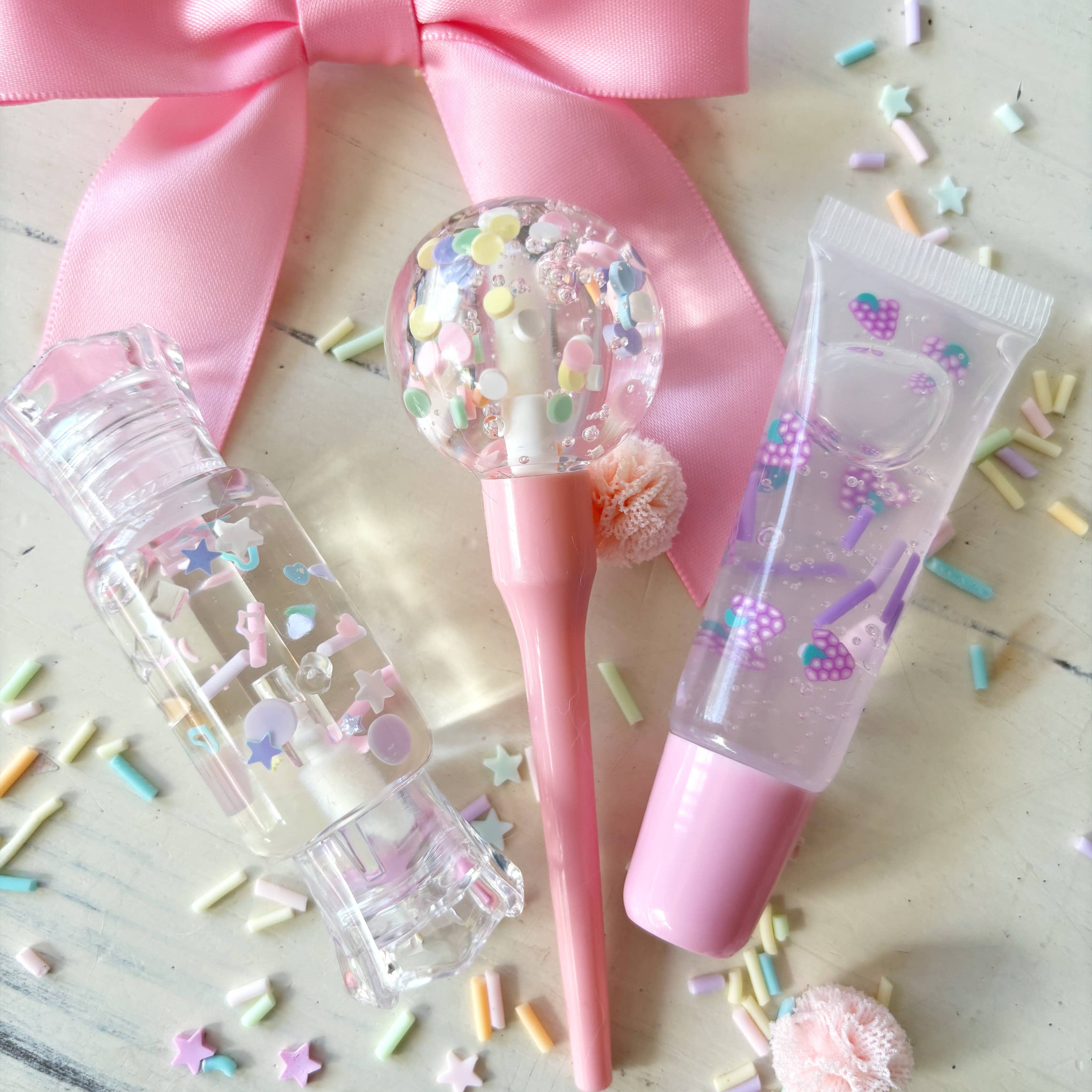 Pink beauty product set with a bow on a wooden surface with colorful sprinkles.