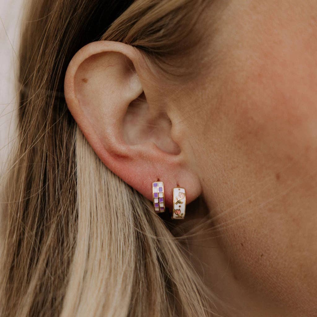 Close-up of an ear wearing two small hoop earrings with a neutral background