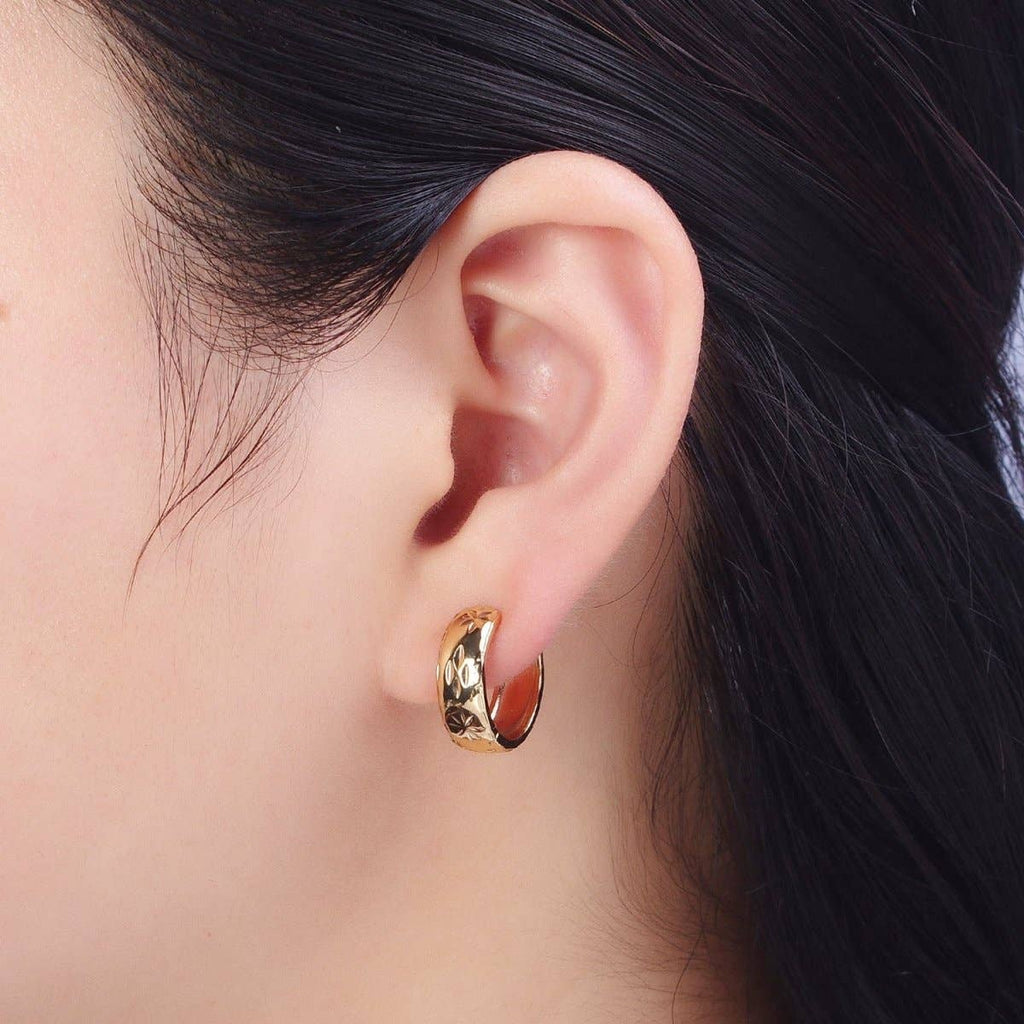 Close-up of an ear wearing a gold hoop earring with dark hair.