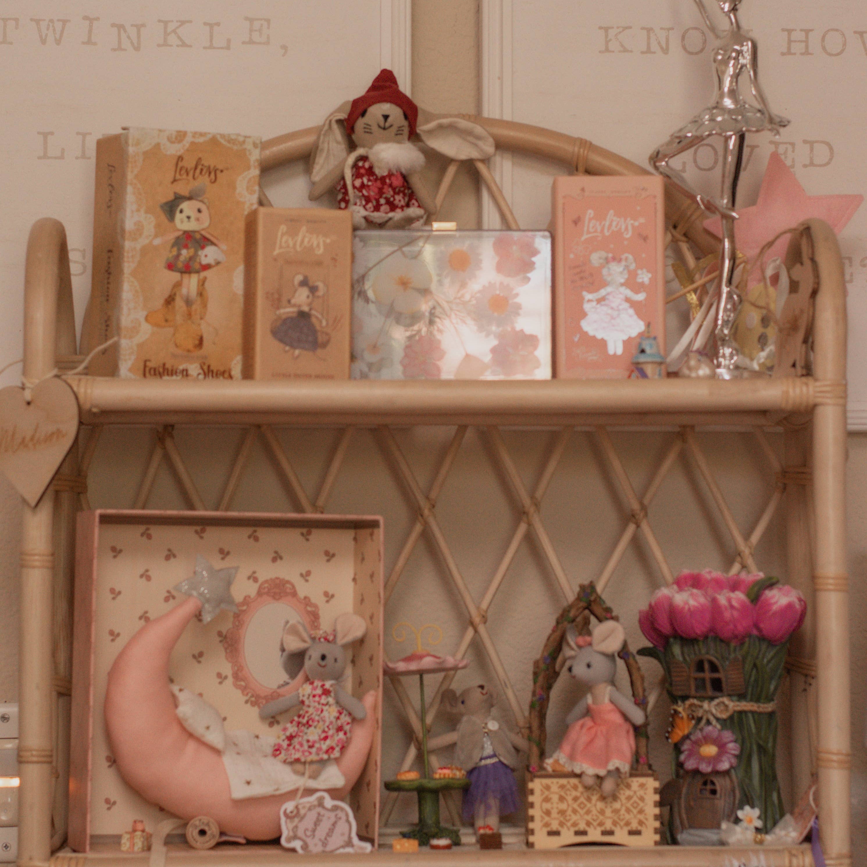 Decorative shelf with various small figurines and books against a beige wall.