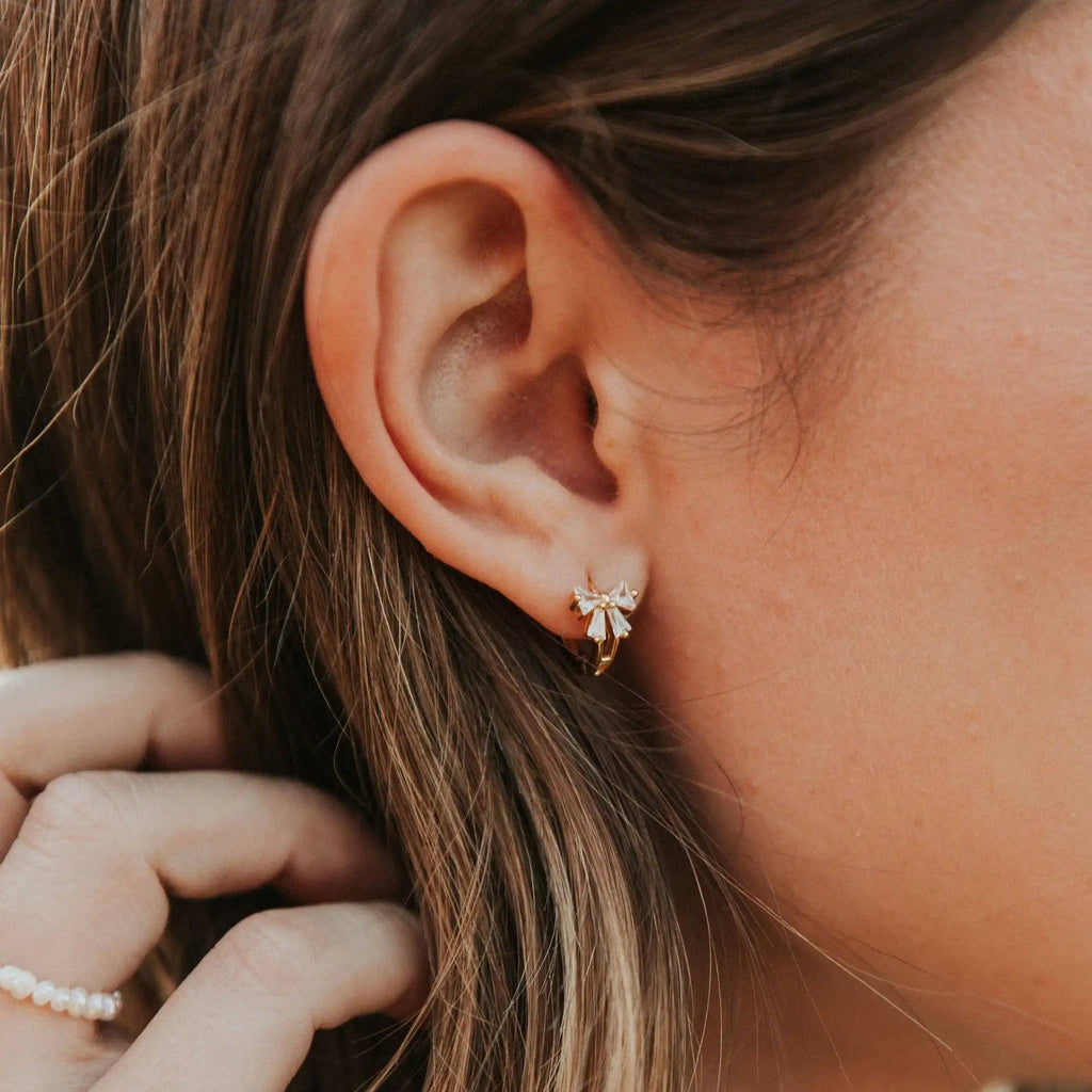 Close-up of an ear wearing a delicate earring with a blurred background
