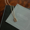 Gold necklace with a cross pendant on a green card with text