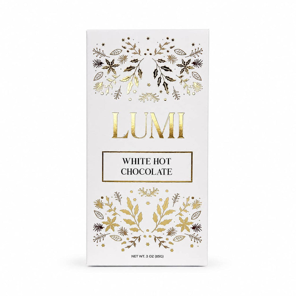 A 3 oz box of Lumi White Hot Chocolate, featuring a clean white packaging design with elegant gold foil botanical illustrations and the brand name 'LUMI' in gold lettering.