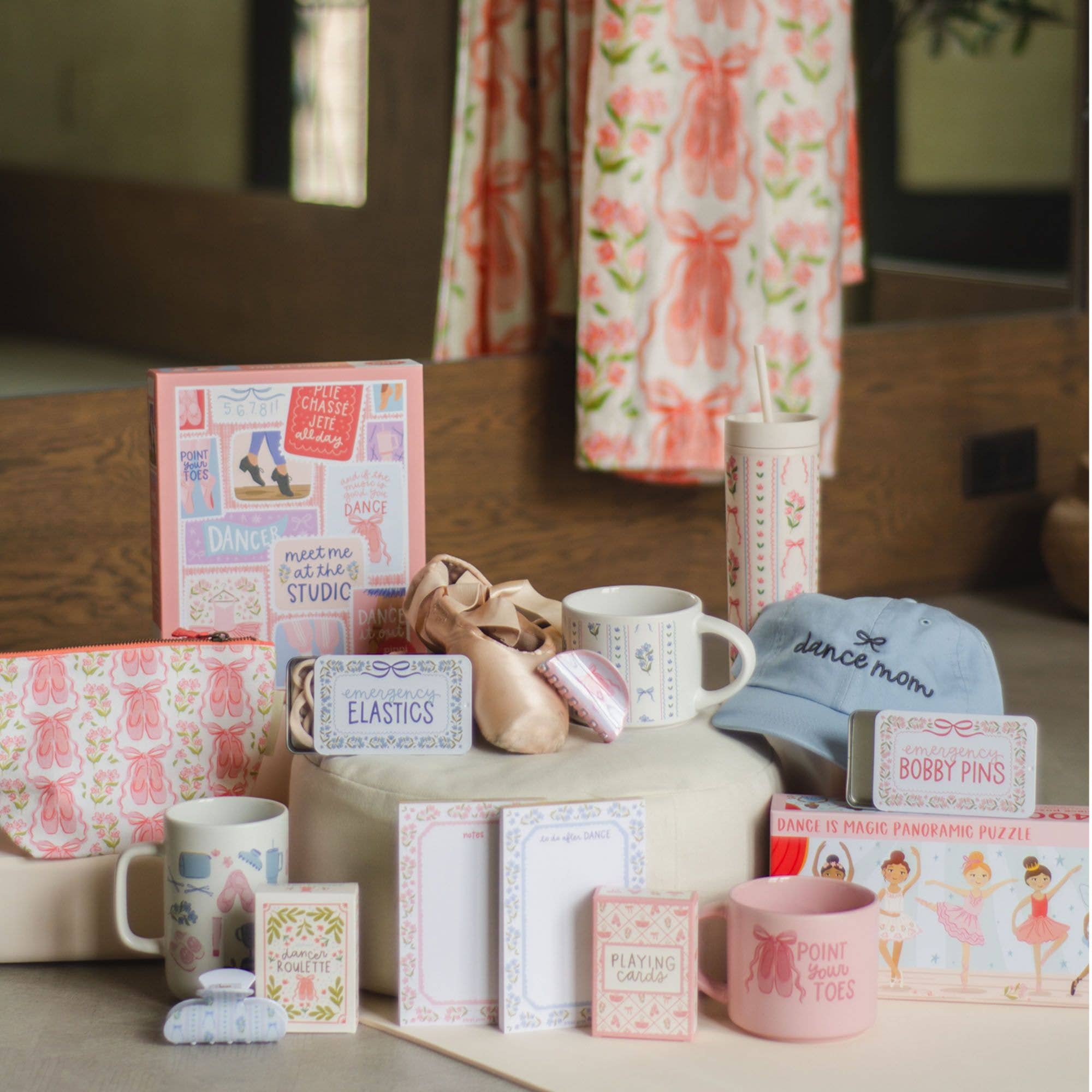 Collection of items including mugs, boxes, and a hat on a surface with a floral curtain in the background.
