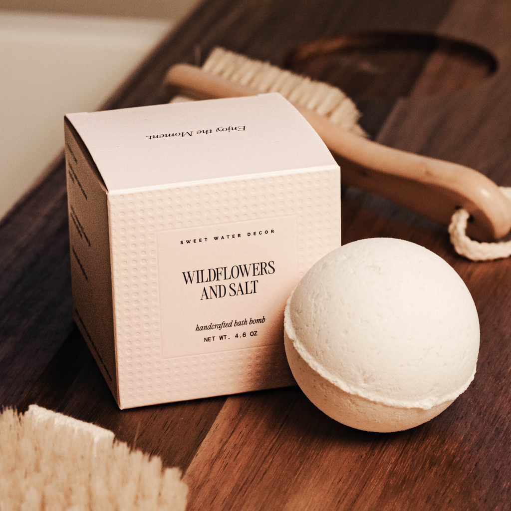Bath bomb with packaging labeled 'Wildflowers and Salt' on a wooden surface.