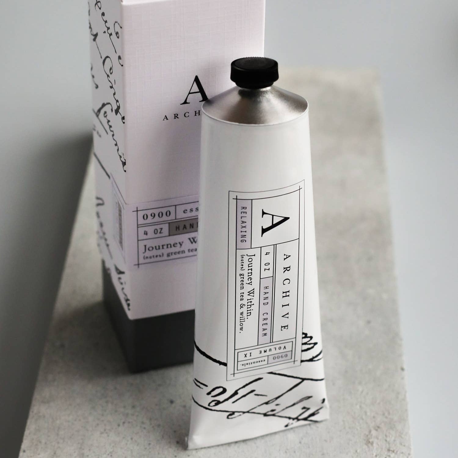 Hand cream bottle with packaging on a gray surface