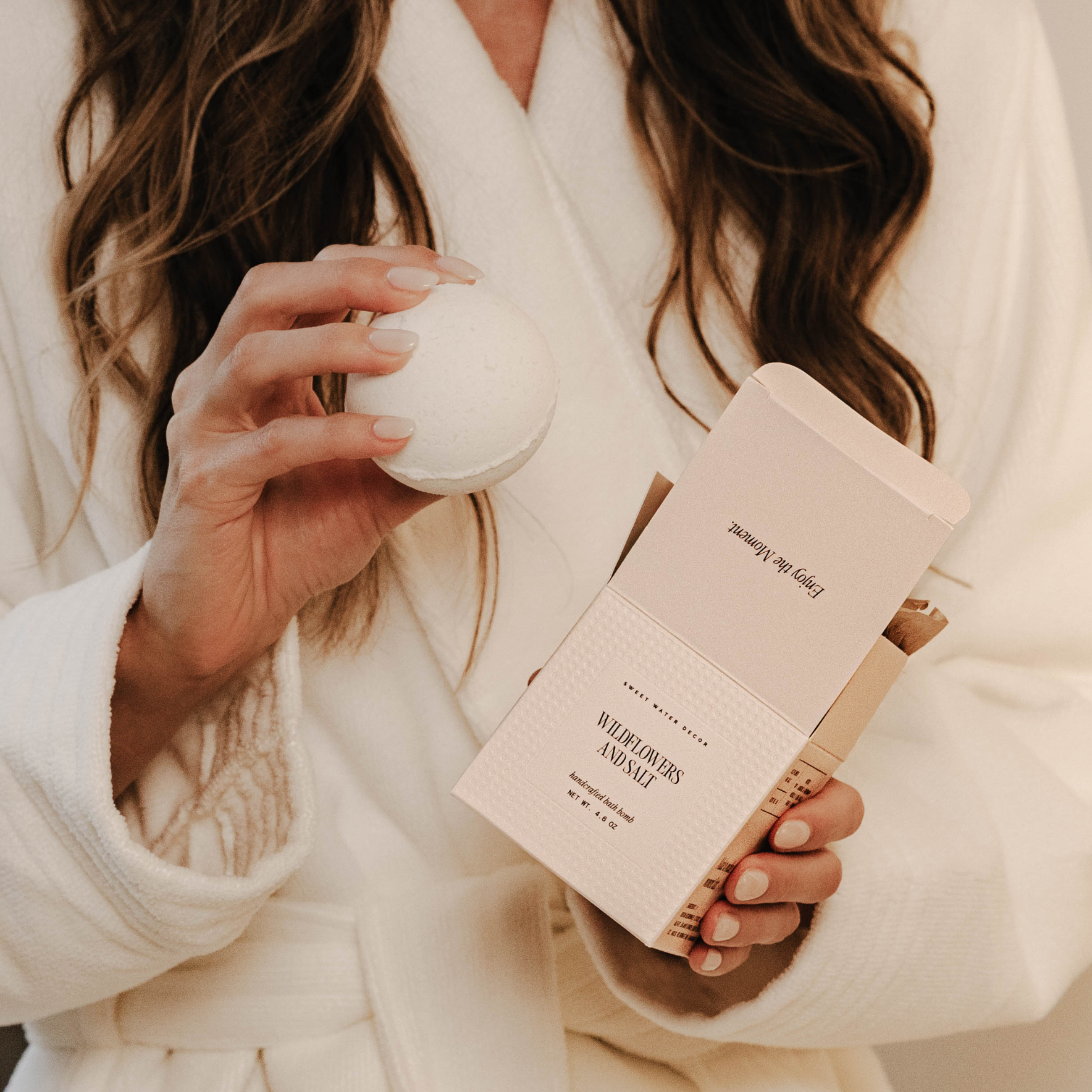 Person holding a white candle and a pink book titled 'Waldorf's Animal' in a cozy setting.