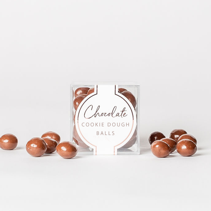 Box of chocolate cookie dough balls with some outside the box on a white background