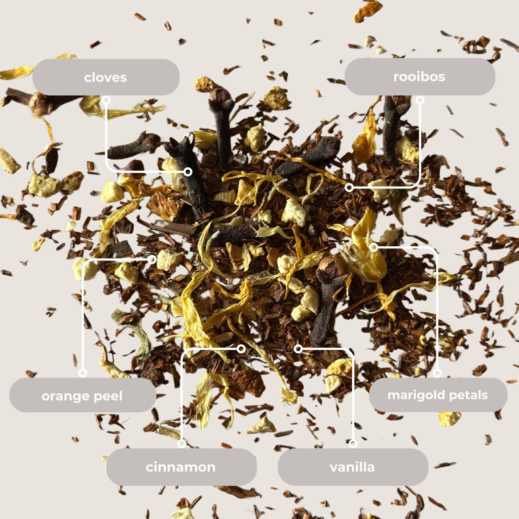 Spices and herbs including cloves, rooibos, orange peel, marigold petals, cinnamon, and vanilla on a light background.