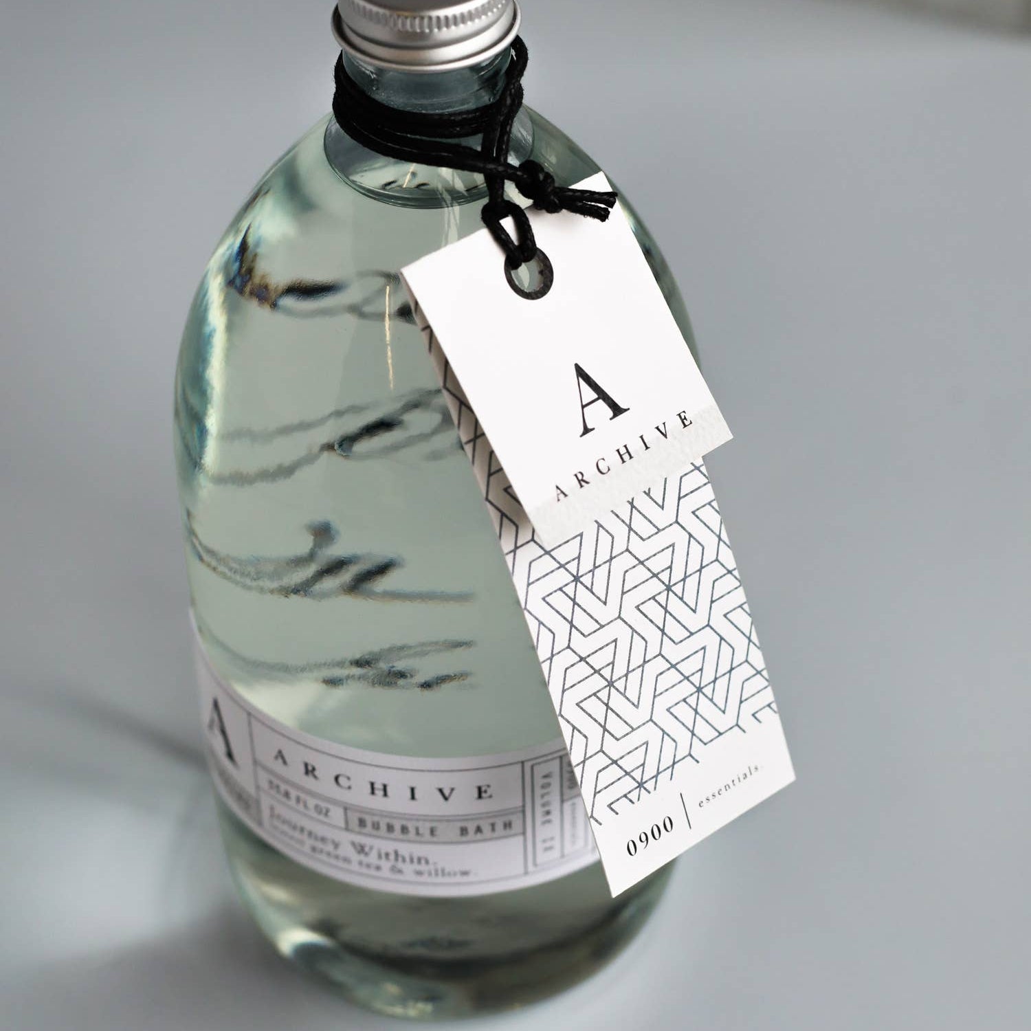 Bottle of 'Archive' with a label and tag on a gray surface