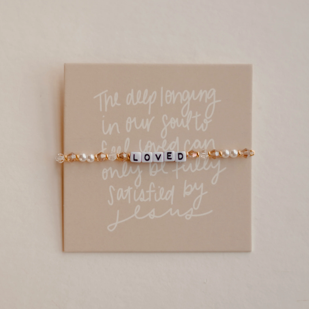 Bracelet with 'LOVED' beads on a card with text