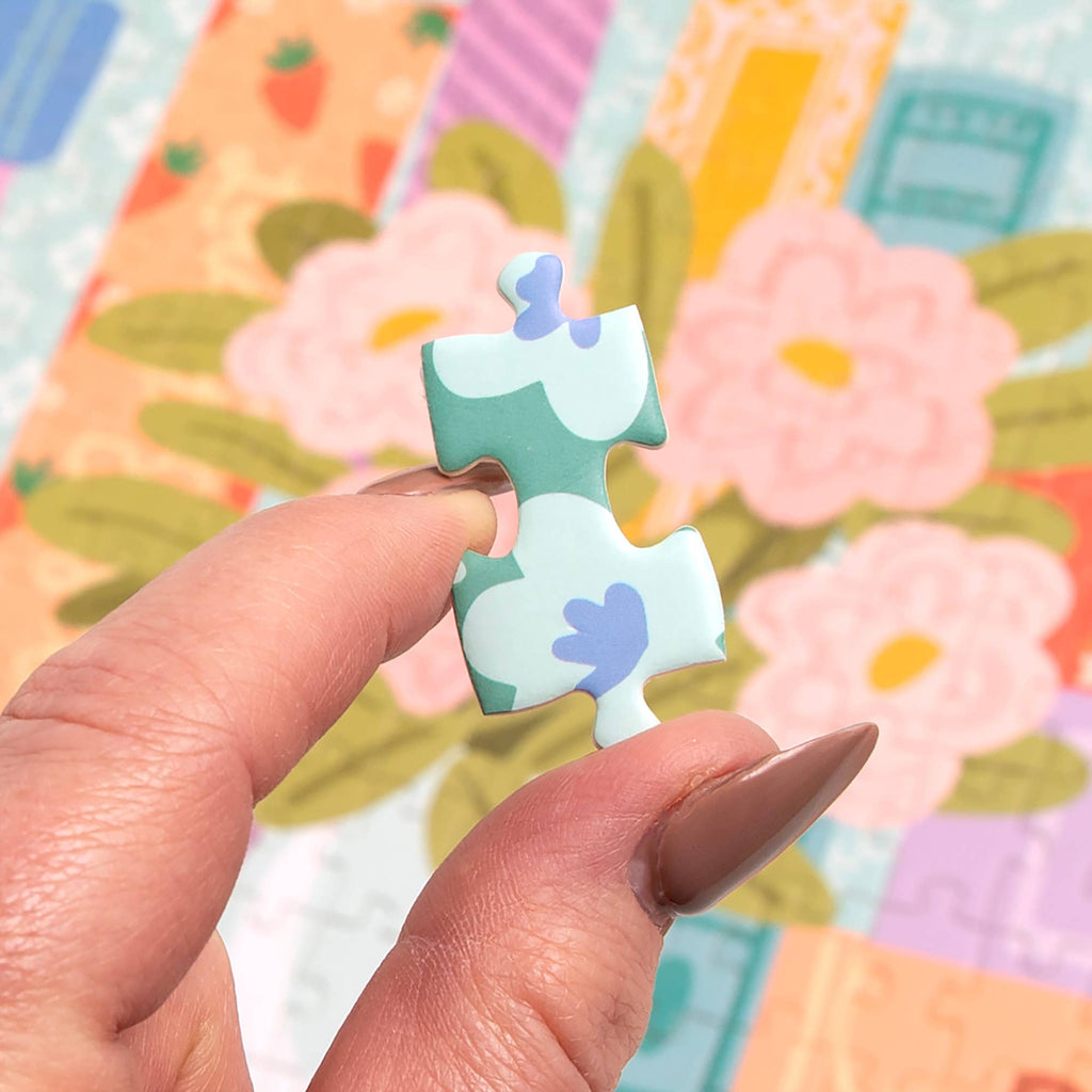 Hands holding pastel-colored puzzle pieces from the Jane Austen bookshelf puzzle.