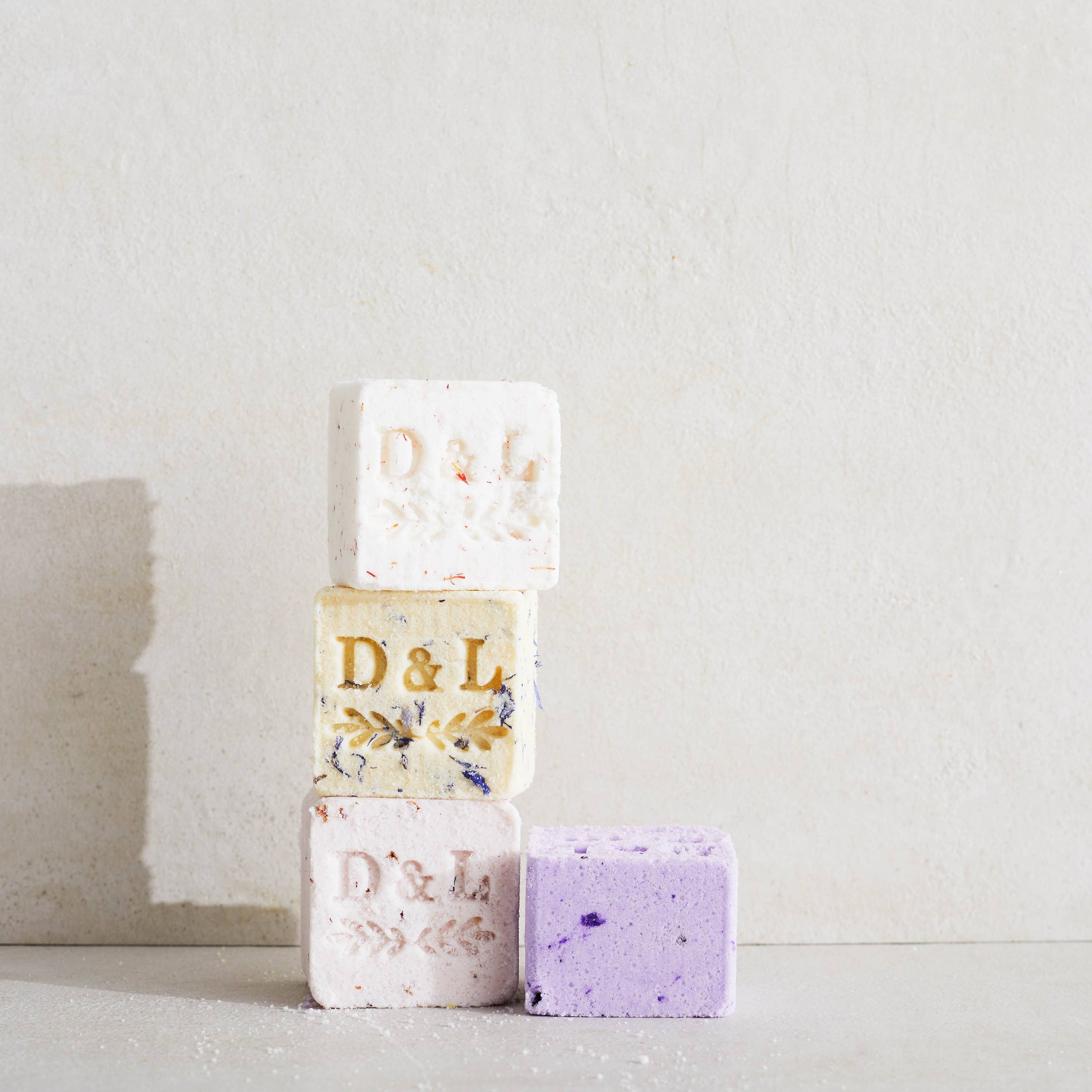 Three soap bars stacked on a light surface with a neutral background