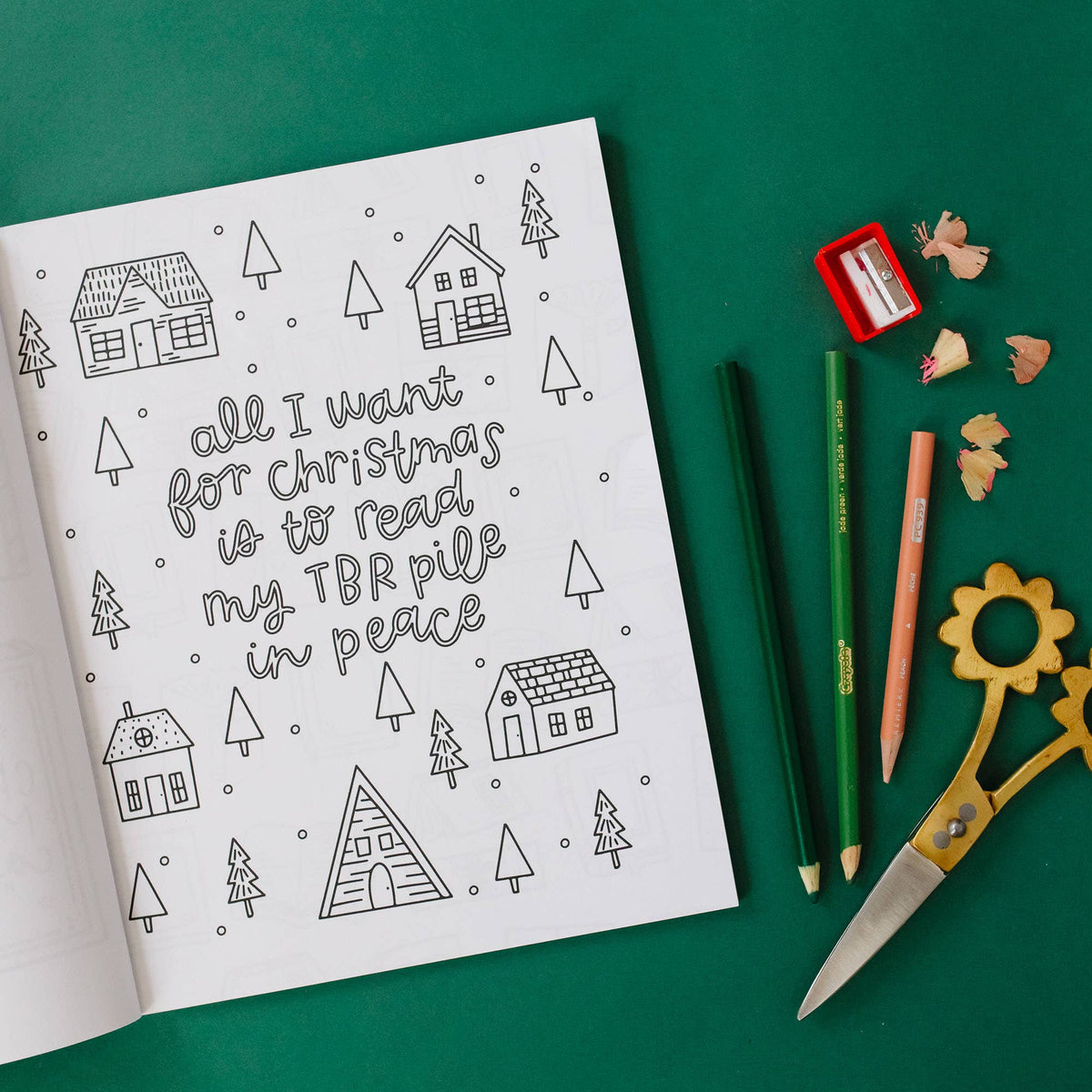 Coloring book page with Christmas-themed text and illustrations on a green background with stationery items.