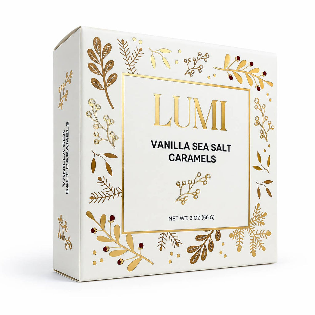 A white rectangular box of LUMI Vanilla Sea Salt Caramels, decorated with elegant gold botanical illustrations and a gold border around the central label.