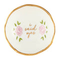 Round white dish with gold rim, pink roses, and 'i said yes' text on a white background