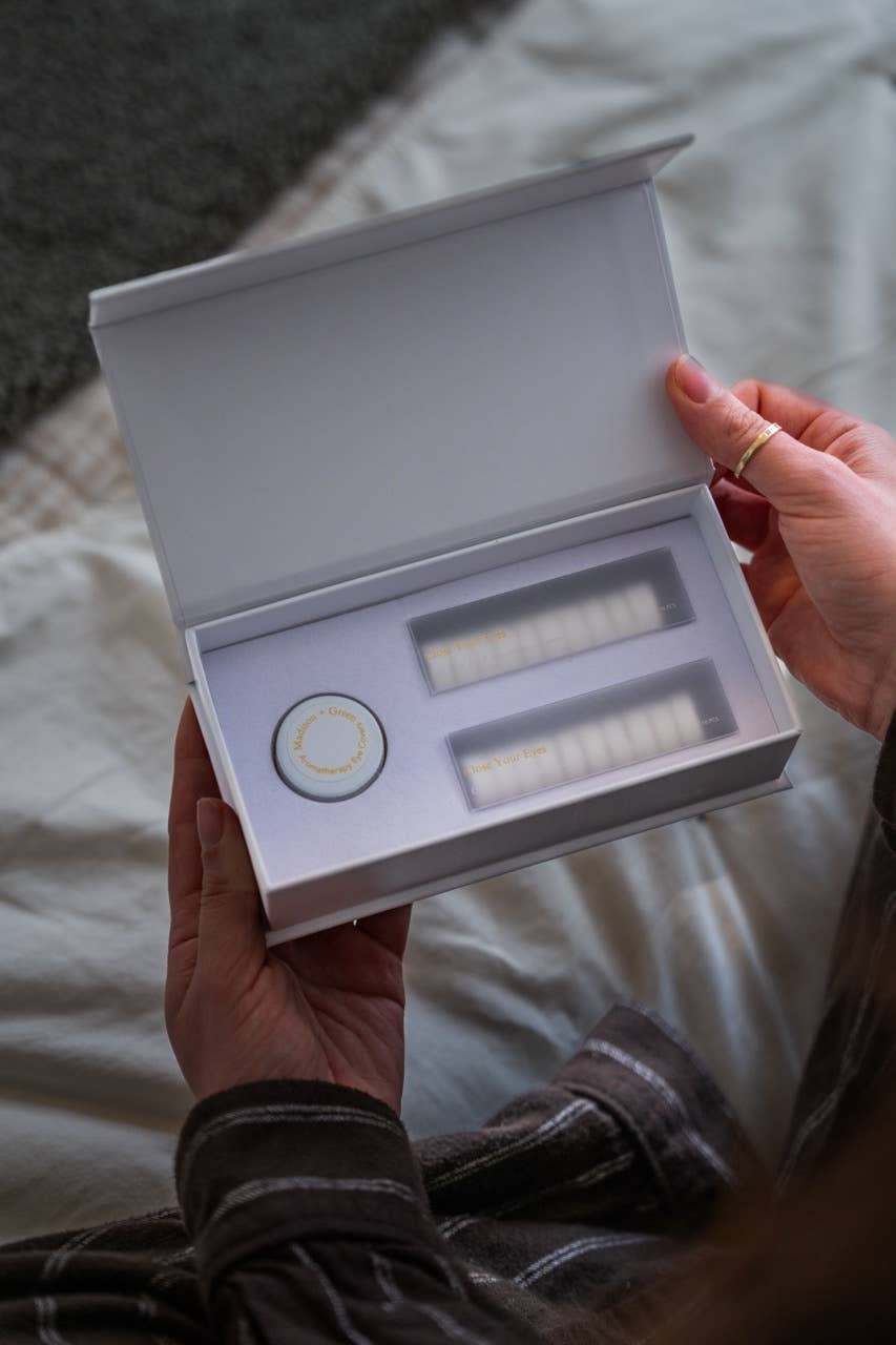 Person holding a white box with dental aligners on a bed