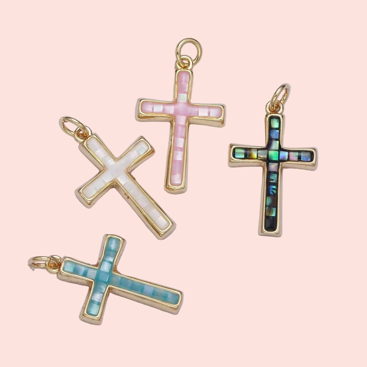 Four gold cross pendants with different colored inlays on a light purple background