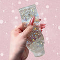 Clear gel with colorful glitter held by a hand on a neutral background
