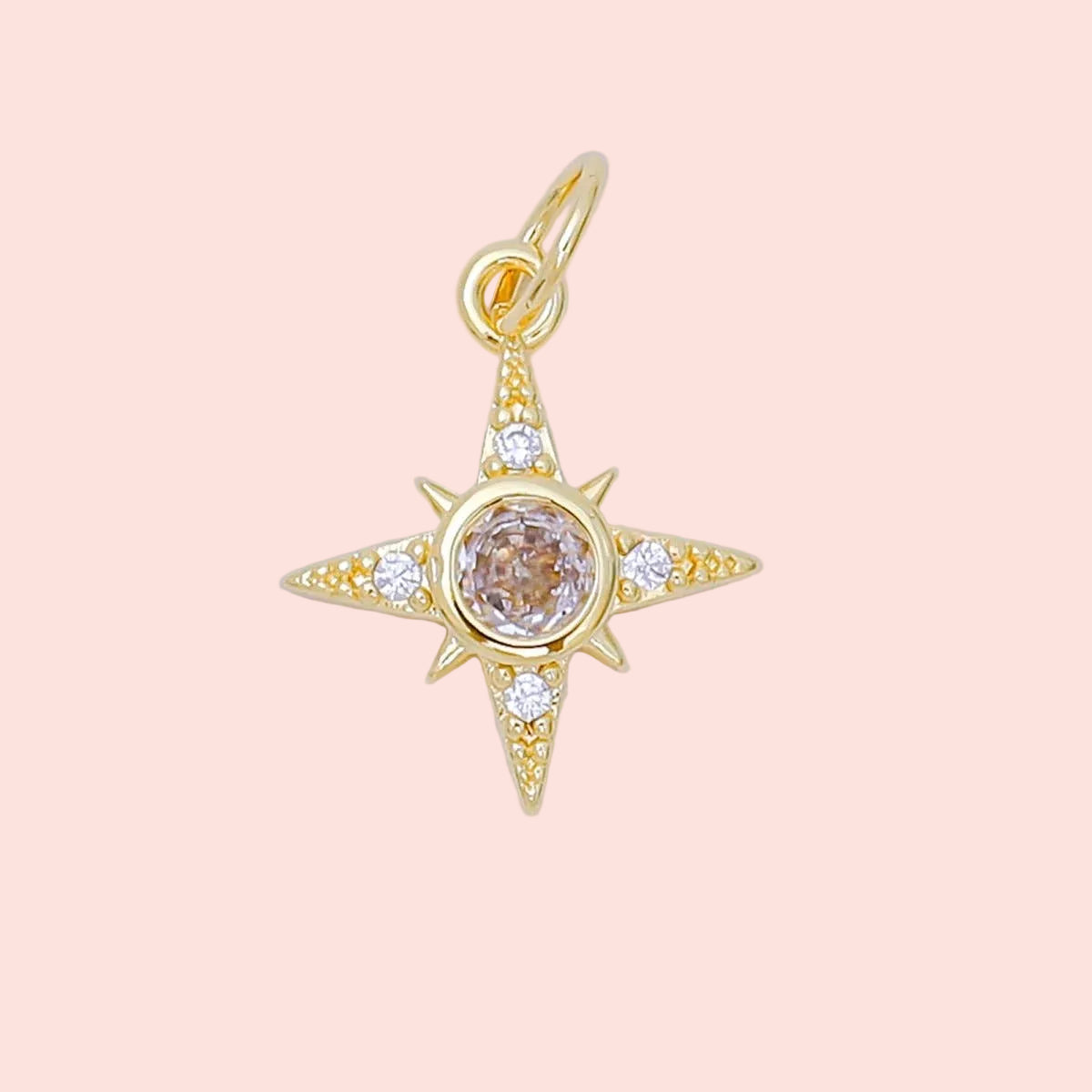 Gold star-shaped pendant with a central gemstone on a light gray background