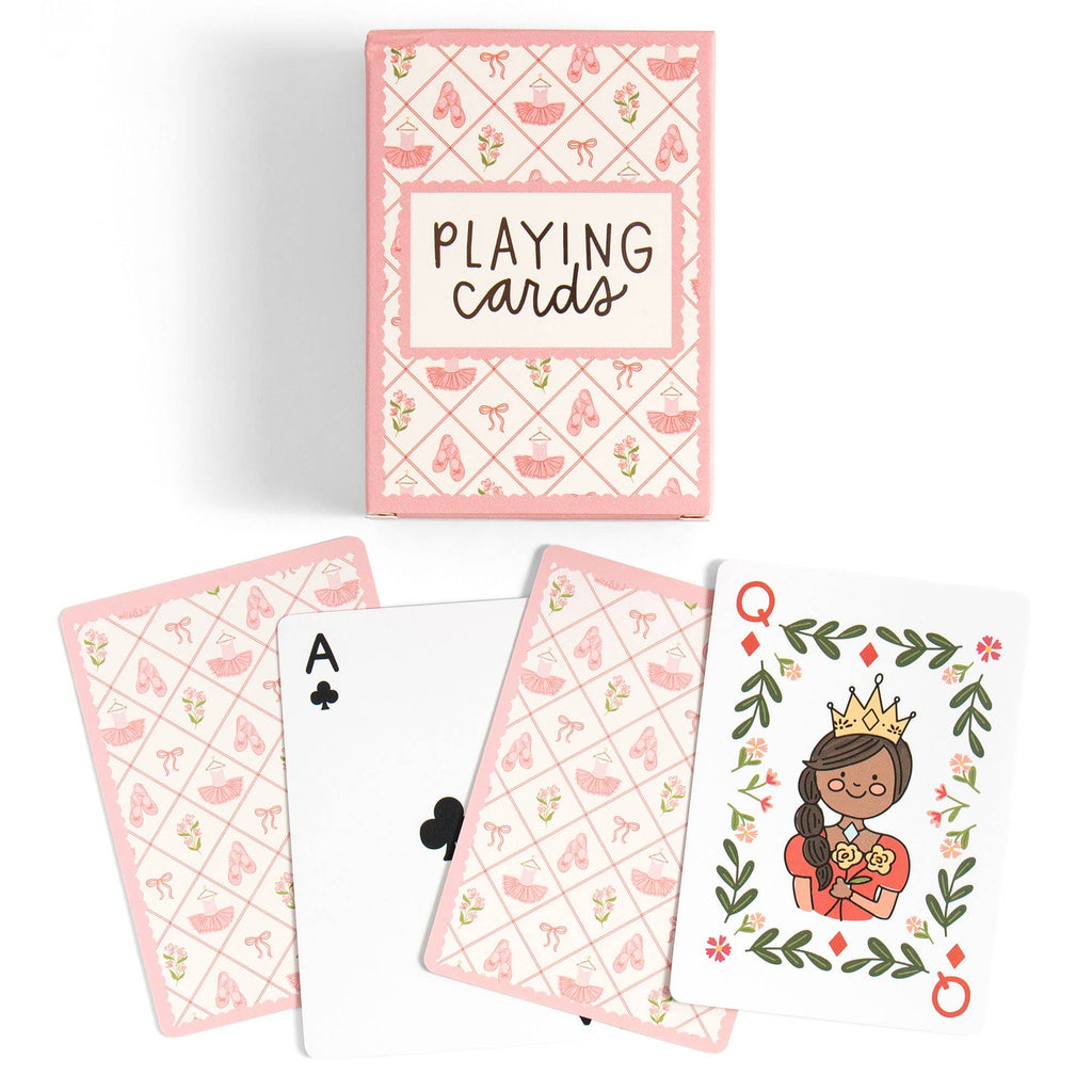 A boxed deck of playing cards with several cards fanned out below. The box and card backs have a pink patterned design with small illustrations, and one visible card shows a crowned queen illustration on a white background.