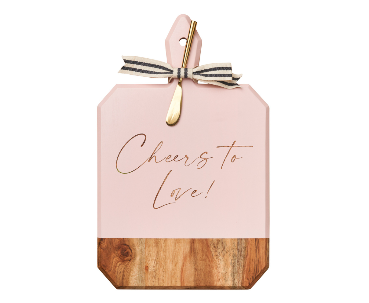 Pink cutting board with wooden bottom and 'Cheers to Love!' text, tied with a ribbon on a white background.