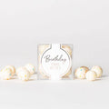 Packaged birthday cake batter with decorative balls on a light gray background