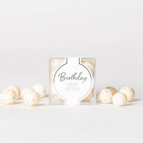 Packaged birthday cake batter with decorative balls on a light gray background