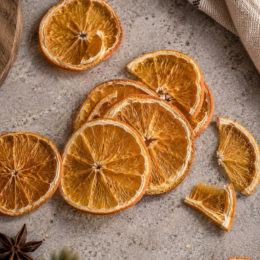 loose slices close-up: Whole and broken dried orange slices scattered on a gray surface beside star anise and a linen cloth.