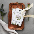 Flower bath milk packaging on a copper tray with flowers and ribbon on a gray background