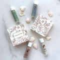 Cosmetic products with floral packaging and white flowers on a light background