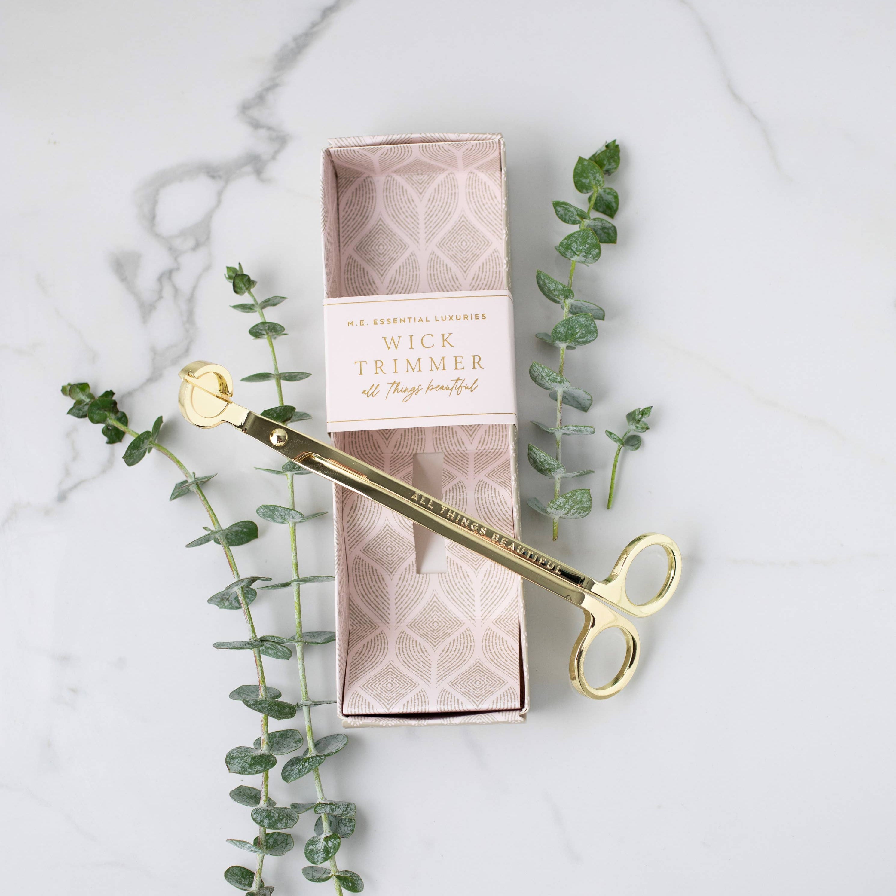 Gold floral trimmer with packaging on a marble surface