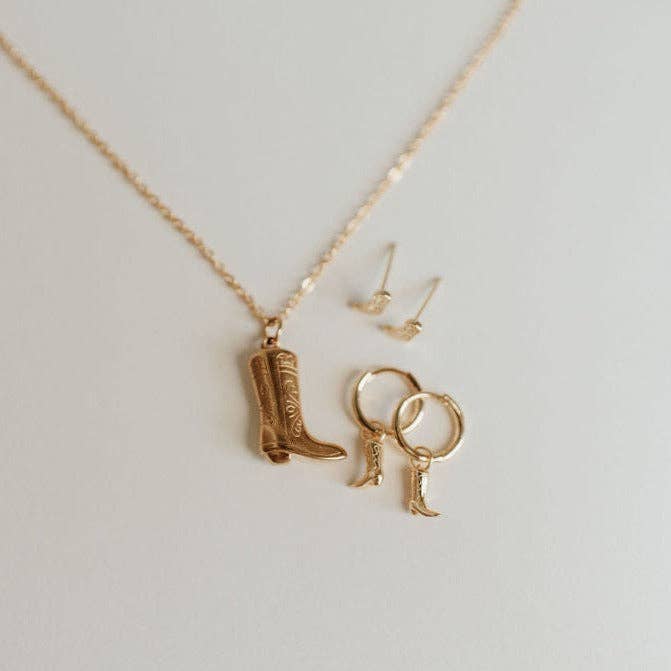 Gold jewelry set with boot-shaped pendant on a light gray background
