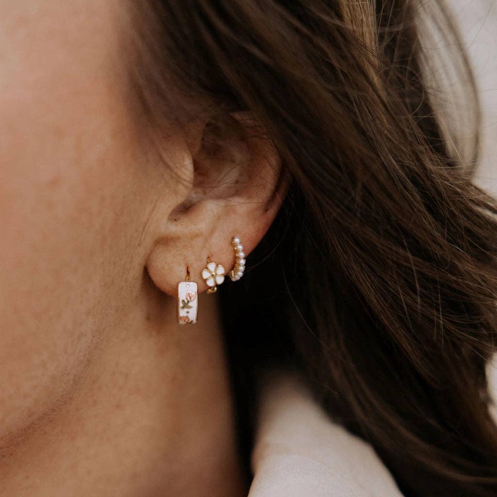 Close-up of an ear wearing multiple earrings with a blurred background