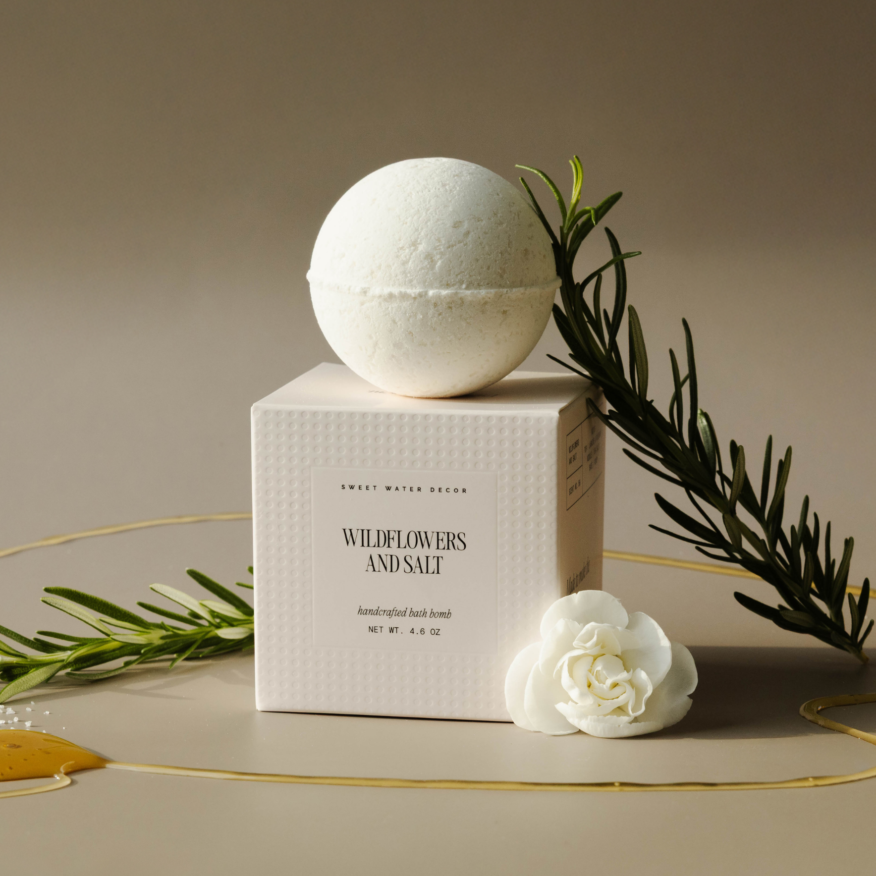White bath bomb on a box labeled 'Wildflowers and Salt' with decorative elements on a beige background