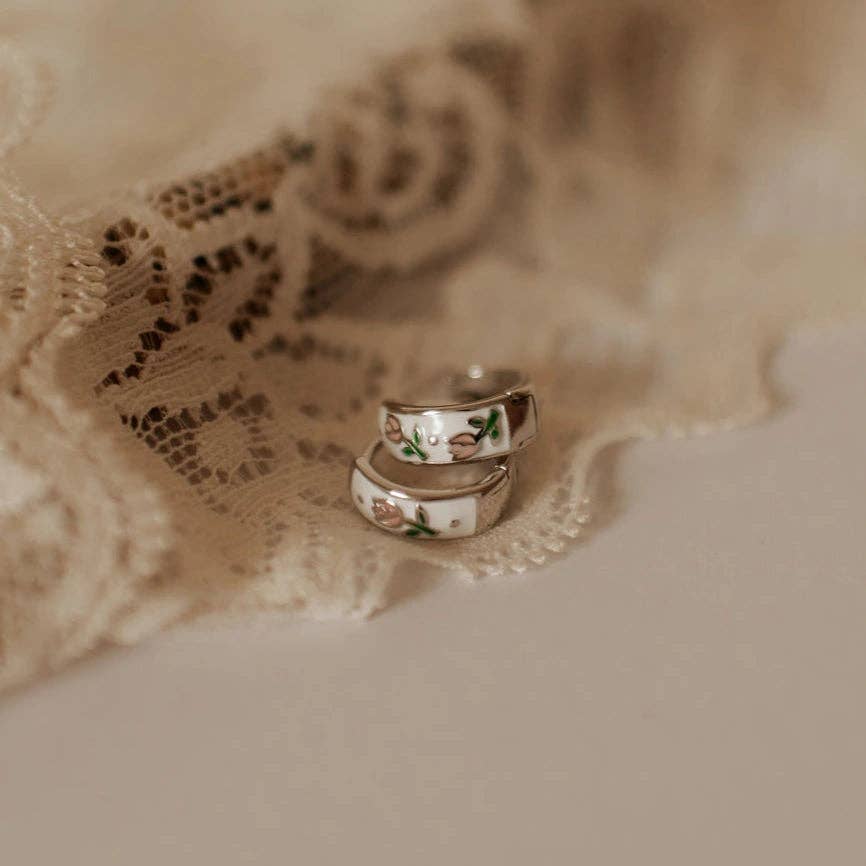 Two floral-patterned rings on a lace fabric background